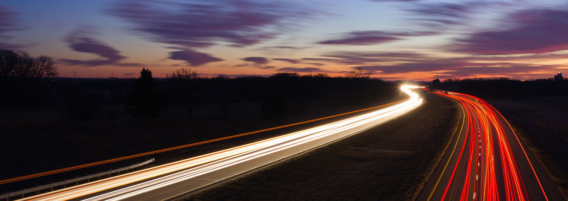 AUTOVÍA CON TRÁFICO POR LA NOCHE Y FORMAN HACES DE LUZ LOS FAROS DE LOS COCHES